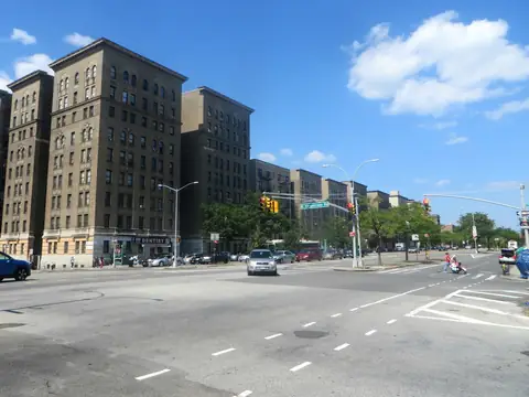Tall brick pre-war apartment buildings along the Grand Concourse in the Bronx under a blue sky