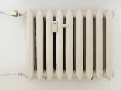 A white cast iron radiator standing against a plain wall