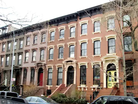A long row of brownstone houses with high stoops on Prospect Place in Prospect Heights, Brooklyn