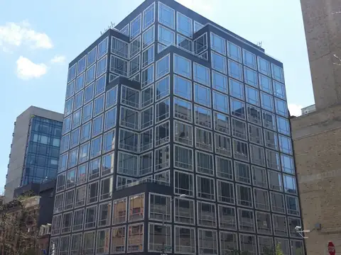 A modern glass condominium building against a blue sky in New York