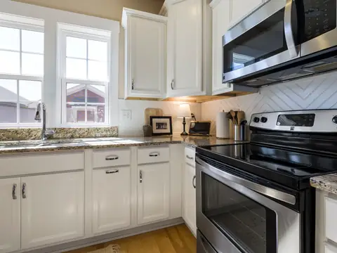 A bright kitchen with white base cabinets under the counter and the sink