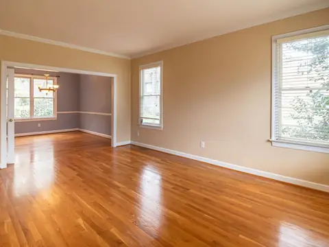 A bright empty room with polished hardwood floors and freshly painted walls