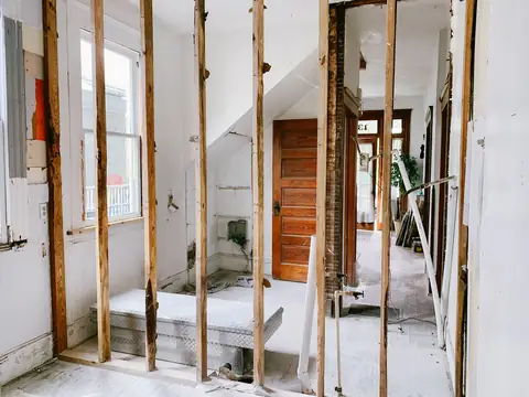 A bright room with its wall board stripped back to the wooden studs during repairs