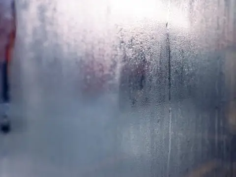 Moisture droplets running down the inside of a fogged window