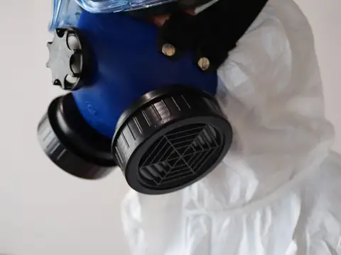 A respirator mask resting on a white protective suit