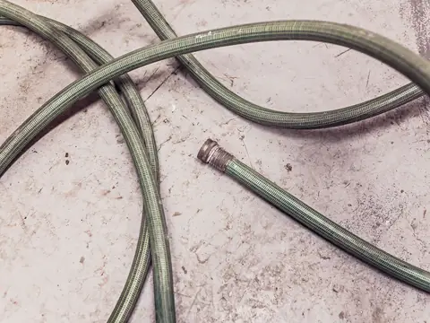 Braided hoses lying in loops across a stained floor