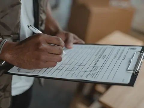 A hand writing notes on a form clipped to a board