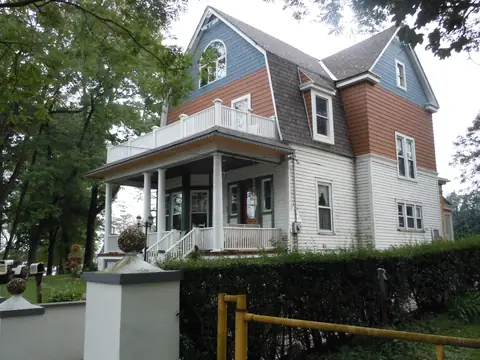 A two-story house with a front porch and a shingled gable on a Staten Island street