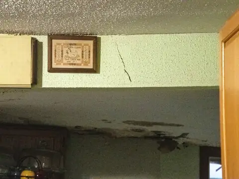 Water stains and cracks running across a ceiling above a doorway