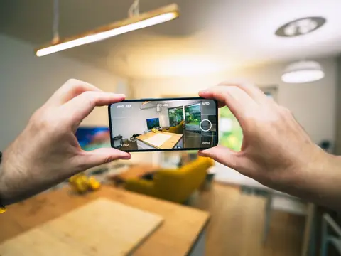 Hands holding a phone up to photograph a living room