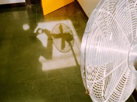 A white fan blowing across a sunlit floor