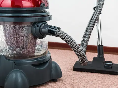 A canister vacuum with a water tank pulling dirt and water out of a carpet
